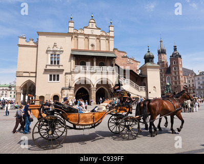 Poland, Cracow. Tourists enjoying a horse-drawn carriage ride in Market Square. Stock Photo