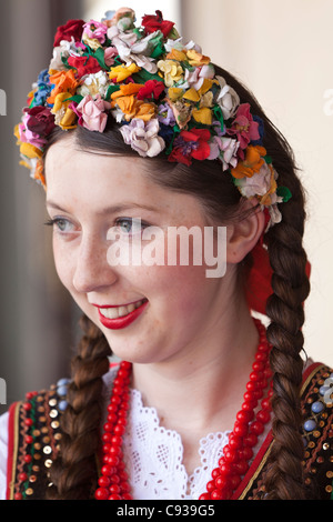 Poland, Cracow. Polish girl in traditional dress applying lipstick ...