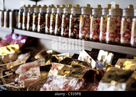 Strawberry flavoured holiday stick of rock in jars and bags of sweets for sale, the perfect holiday beach gift and present. Stock Photo