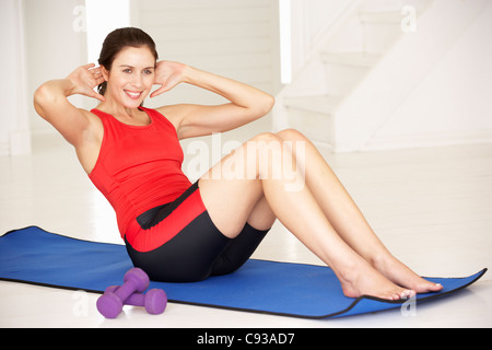 Woman doing sit-ups in home gym Stock Photo