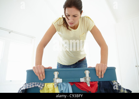 Woman struggling to close suitcase