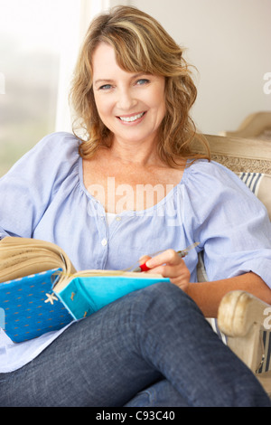Mid age woman writing in notebook Stock Photo