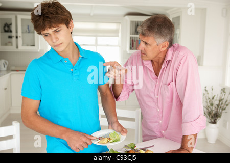 Father making teenage son do housework Stock Photo
