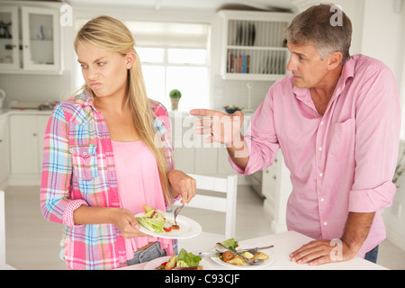 Father making teenage daughter do chores at home Stock Photo