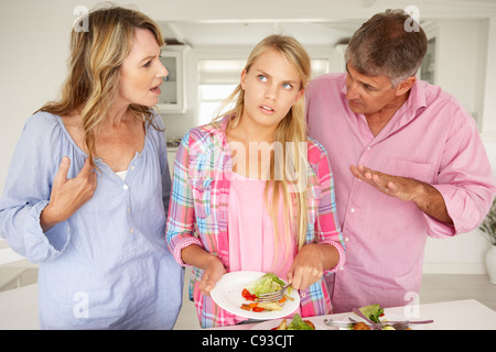 Parents making teenage daughter do chores at home Stock Photo