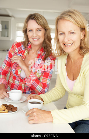 Mid age women chatting over coffee at home Stock Photo