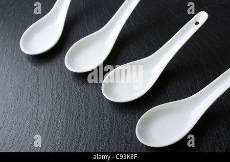 four small white spoons on a table slate Stock Photo