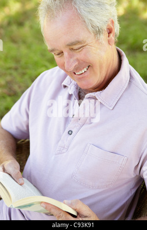 Senior man reading book outdoors Stock Photo