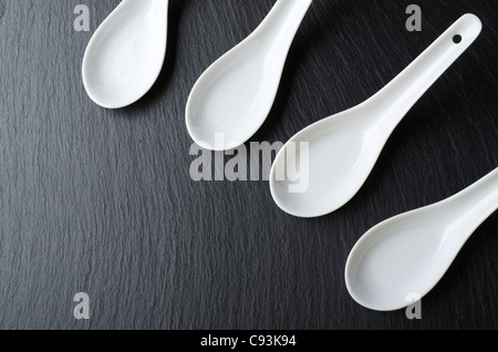 four small white spoons on a table slate Stock Photo