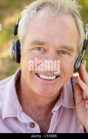 Older man listening to music or a podcast using head phone on his smart ...