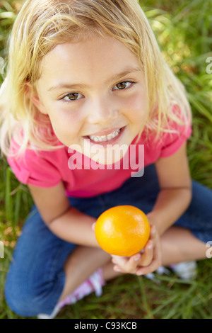 Little girl holding orange outdoors Stock Photo