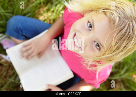 Little girl reading book outdoors Stock Photo