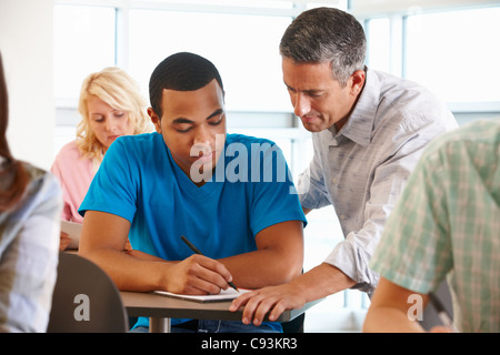 Tutor helping student in class Stock Photo