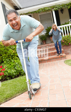 Senior couple playing with children's scooter Stock Photo