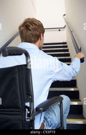 Man in wheelchair at foot of stairs Stock Photo