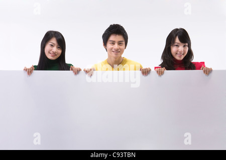 Portrait of three friends holding blank sign Stock Photo