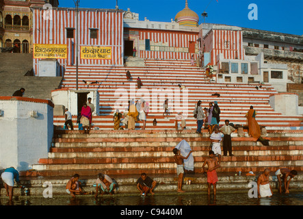 Pilgrims bathing on the brightly painted steps of Kedar Ghat, on the banks of the River Ganges, Varanasi, Uttar Pradesh, India Stock Photo