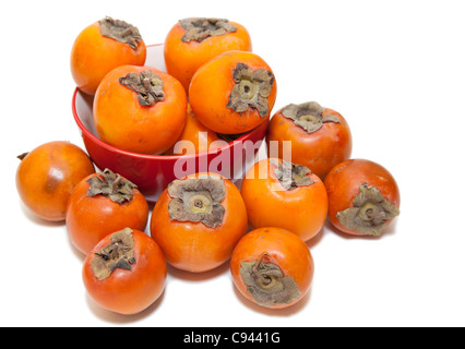 Red juicy persimmons isolated on white background. Laying in red plate Stock Photo