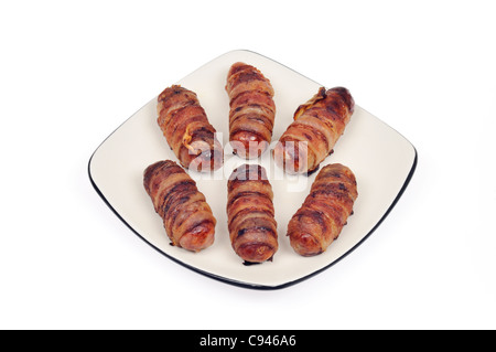 Cooked pigs in blankets sausages wrapped in bacon on white plate on white background cutout. Stock Photo