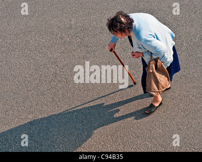 Overhead view older hunchback woman crossing road - France. Stock Photo