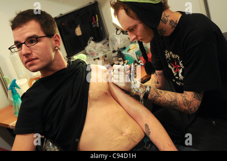 12.11.2011 Warsaw, Poland. Tattooist creates a tattoo on his client's arm during the first day of tattoo, body painting and pierceing show - 'Body Art Convention' in Palace of Culture and Science in Warsaw. Stock Photo