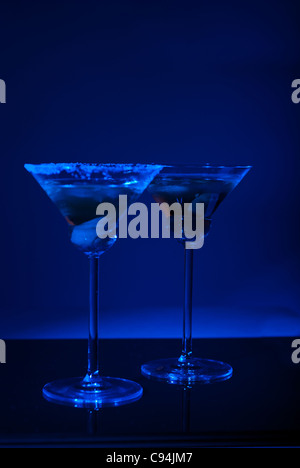 Two martini glasses with olives in darkness with blue light Stock Photo