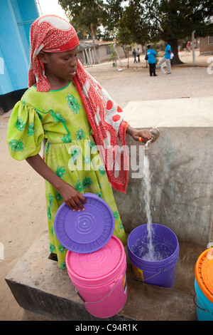 A young girl fetches water at a well in Dar es Salaam, Tanzania, East Africa. Stock Photo