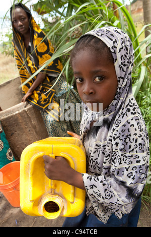 A young girl waits to draw water from a well in Dar es Salaam, Tanzania, East Africa. Stock Photo