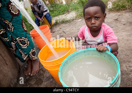 A child sits with dirty water at a well outside Dar es Salaam, Tanzania, East Africa. Stock Photo