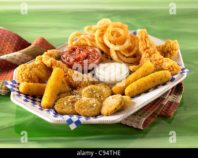 Mixed appetizer of onion rings, chicken wings, fried zucchini with sauces Stock Photo