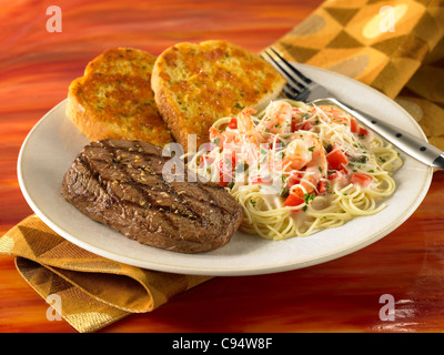 Sirloin and shrimp pasta dinner served with garlic bread Stock Photo