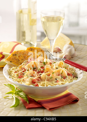 Shrimp scampi pasta topped with Parmesan cheese and served with garlic bread and white wine Stock Photo