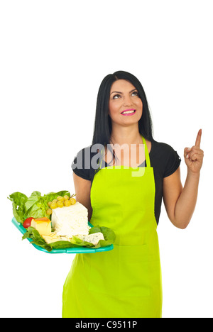 Smiling cheese maker woman holding plateau with different cheese ,pointing and looking up to copy space isolated on white Stock Photo