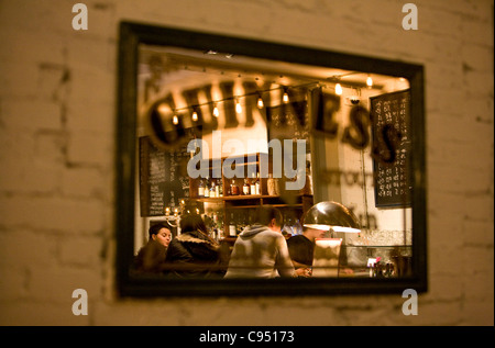 Reflection of people in Guinness framed mirror picture in pub. Stock Photo