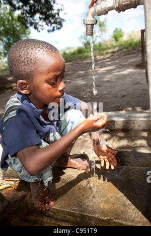 A young child drinks water from a well in Dar es Salaam, Tanzania, East Africa. Stock Photo
