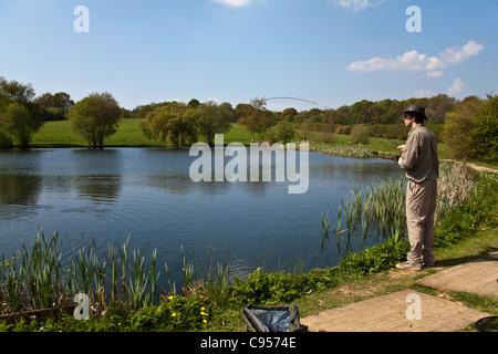 Fisherman catching a rainbow trout. Blackwool Farm trout fishery, West Sussex, England,United Kingdom. Stock Photo