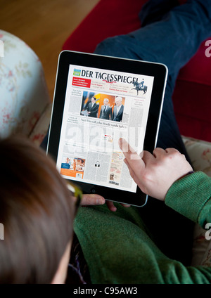 Woman using iPad tablet computer to read digital edition of Der Tagesspiegel newspaper in Germany Stock Photo