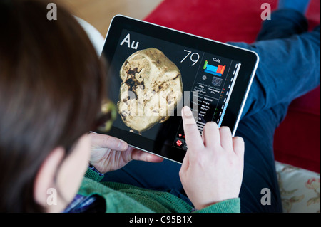 Woman using iPad tablet computer to study chemistry of gold using science application of the Periodic Table Stock Photo