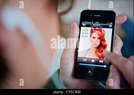 Woman listening to music on iTunes app on an iPhone 4G smart phone Stock Photo