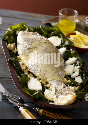 Whole salt crusted red snapper served on a bed of greens Stock Photo
