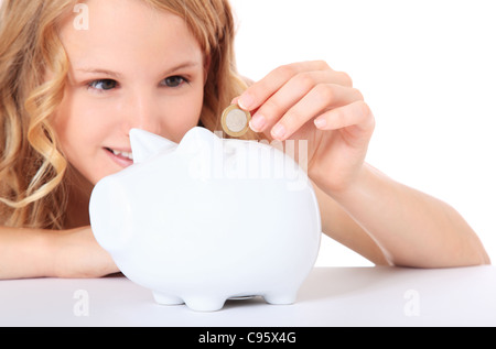 Attractive girl puts money in her piggy bank. All on white background. Stock Photo