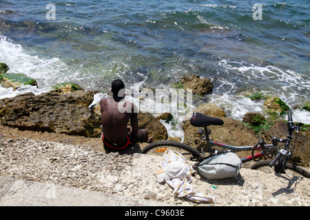 Black man cyclist relaxing and looking away to sea in Palma de Mallorca Majorca Spain Stock Photo