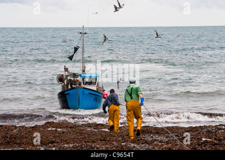 Fishermen in Cadgwith Cornwall helping bring in a crab fishing boat Stock Photo