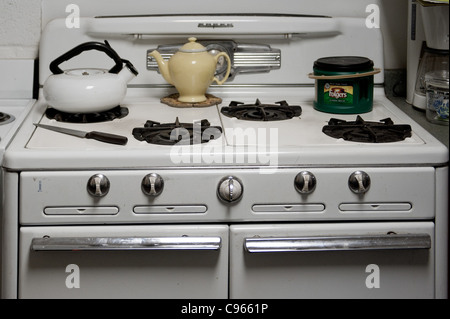 Retro white stove and oven in a kitchen with a yellow teapot on the burner Stock Photo