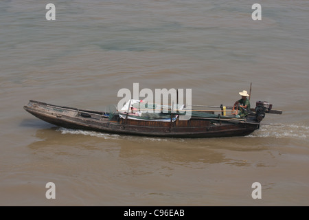 Man in a straw hat at the tiller of a sampan on the Yangtze River at Chizhou, China Stock Photo