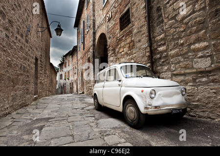 Fiat 500 car parked outside traditional Italian buildings in Gubbio, Umbria, Italy Stock Photo
