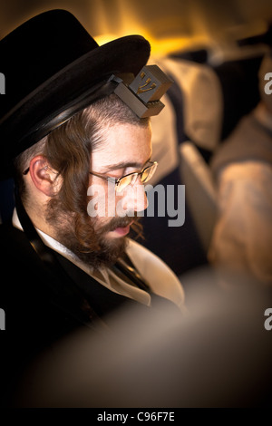 Orthodox Jewish man with tefillin and tallit, sitting alone and praying in  silence Stock Photo - Alamy