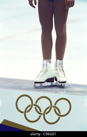 Detail of female figure skater standing atop the podium with the Olympic Rings. Stock Photo