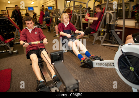 A group of teenage Secondary school boys using various exercise machines (rowing, weight lifting etc)  in the well equipped school gymnasium  a physical education class, Wales UK Stock Photo