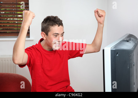 Young male watching and cheering sport on tv